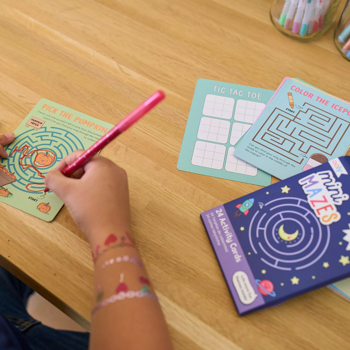 Close up of kid playing a maze game on a table top from an OOLY Mini Mazes Activity Cards set
