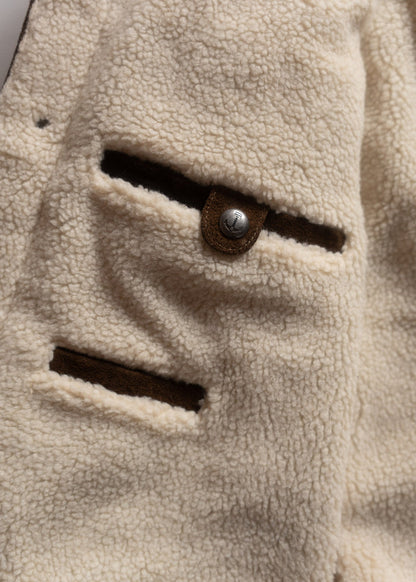Close-up of a beige fleece jacket with two pockets and a metal button, showcasing its soft texture and cozy design.