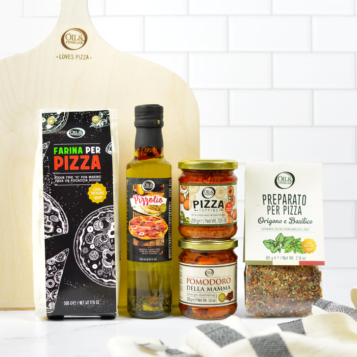 Collection of pizza-making ingredients and tools on a kitchen counter with a white tiled wall background.