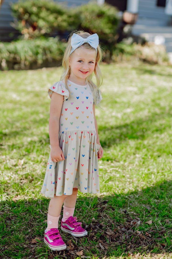 Young girl in a mickey-patterned dress standing on grass