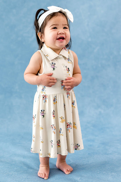 Child wearing a mickey mouse and friends dress with a white headband on a blue background