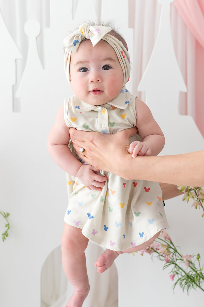 baby in a polo dress with mickey mouse head pattern and matching bow