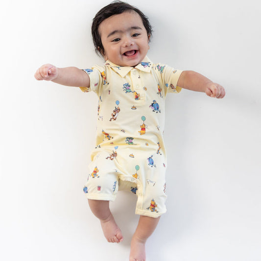 Young smiling toddler wearing the Polo Shortall in Winnie the Pooh Celebration