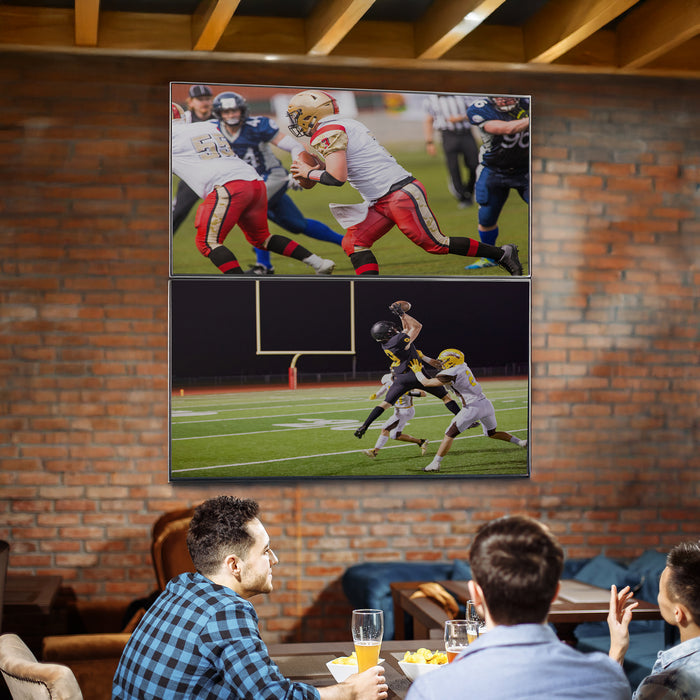 Three people watching a football game on large screen TVs stacked in a brick-walled room.