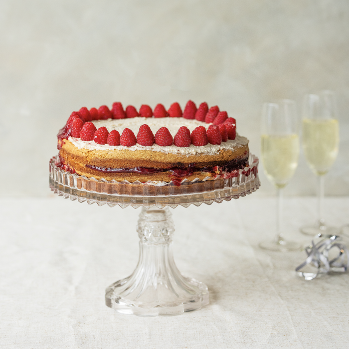 cake on a stand with raspberries and on a white background