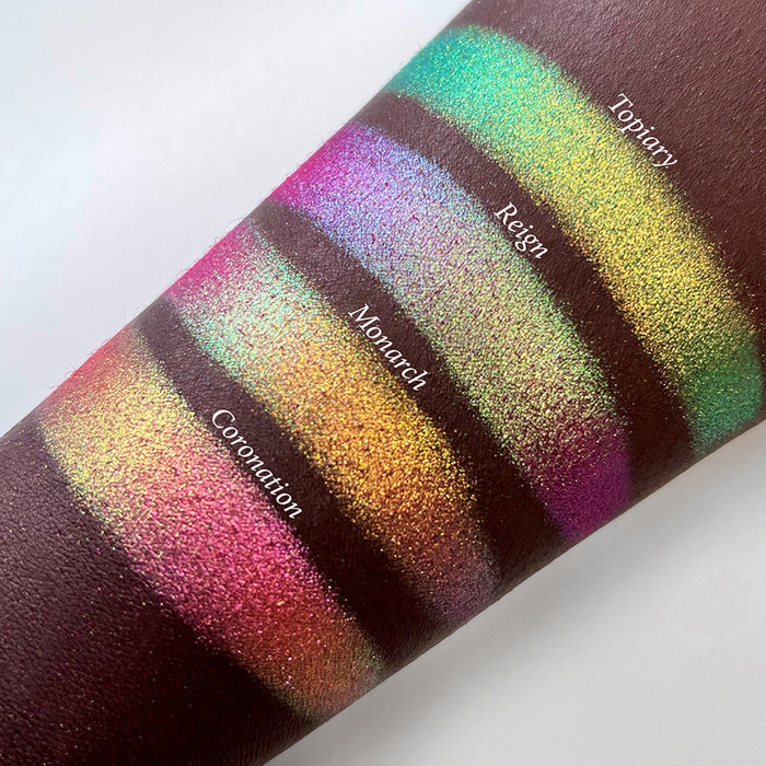 Top angled arm swatches on deep skin tone of Reign Vibrant Multichrome Eyeshadow shifts compared to Topiary, Monarch and Coronation