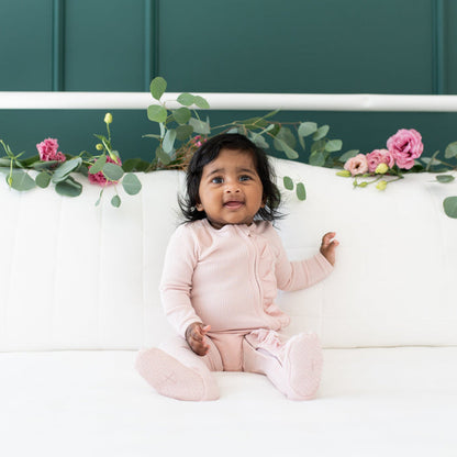 Infant wearing Kyte Baby Ribbed Ruffle Zippered Footie Pajamas in Blush