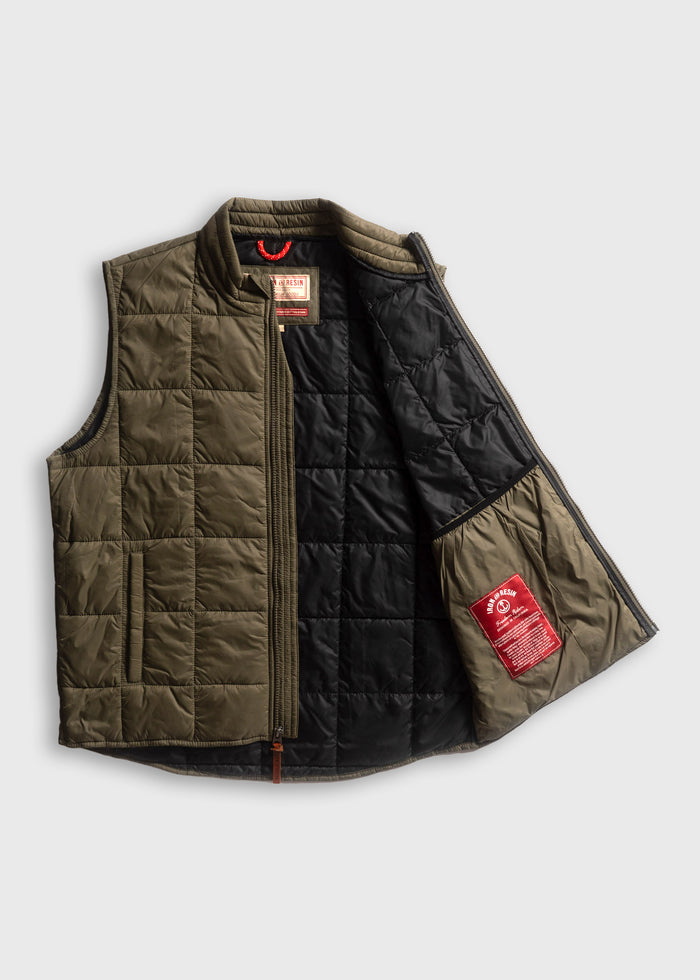 Olive quilted vest with black interior, open to show red label. Features zip closure and two front pockets.