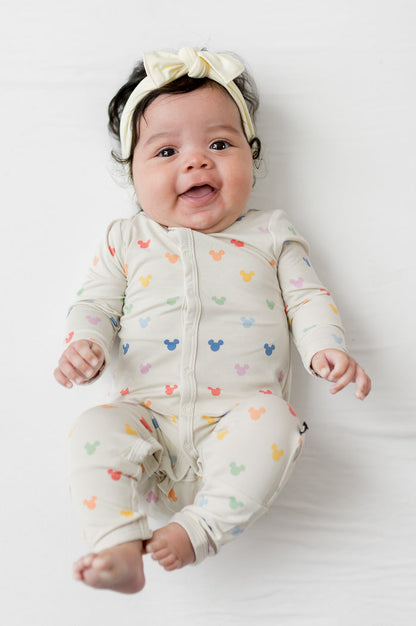 Baby wearing a yellow bow and mickey patterned snap romper