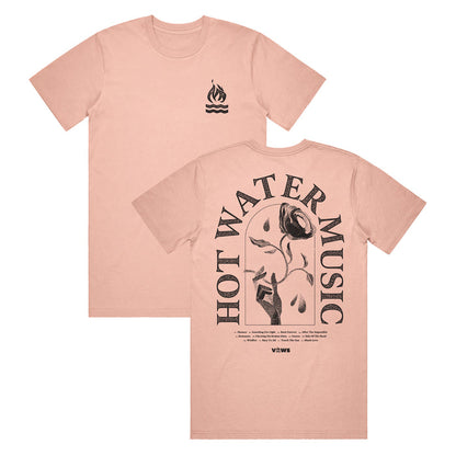pink t shirt. The top right has a small campfire graphic. The back of the shirt has the band name "HOT WATER MUSIC" arched around a hand holding a rose. There is also very small text underneath the main design that is unreadable in the photo.