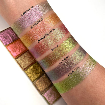 Top angled arm swatches on fair skin tone of Royal Pear Earth Vibrant Multichrome Eyeshadow shifts compared to Cobblestone, Royal Peach, Bronze Fountain, Estate and Iron Gate