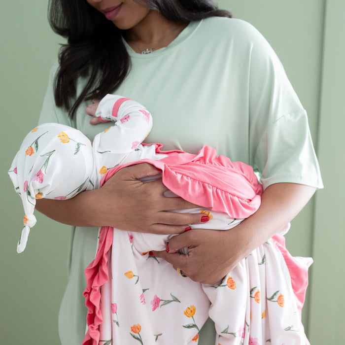 Close up of newborn wrapped in the Ruffle Baby Blanket in Tulip 0.5 being held by her mother