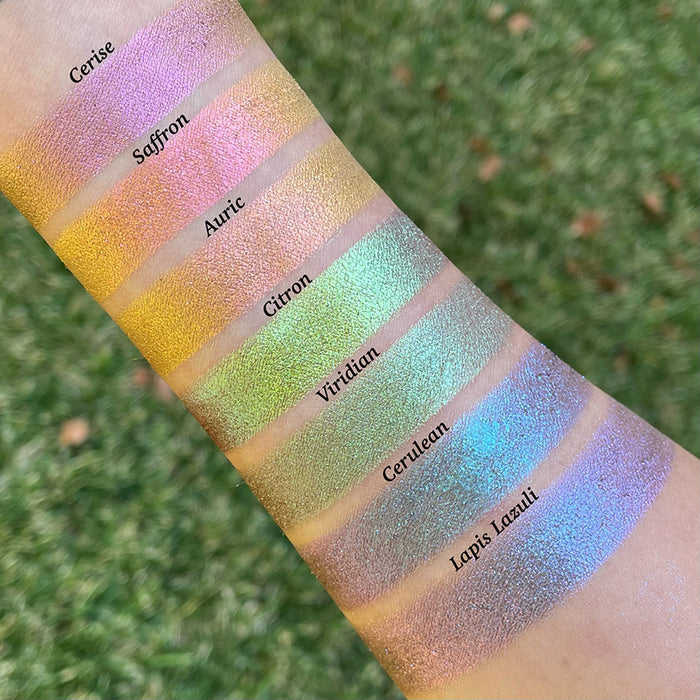 Top angled arm swatches on fair skin tone of Saffron Deep Iridescent Multichrome Eyeshadow shifts compared to Cerise, Auric, Citron, Viridian, Cerulean and Lapis Lazuli