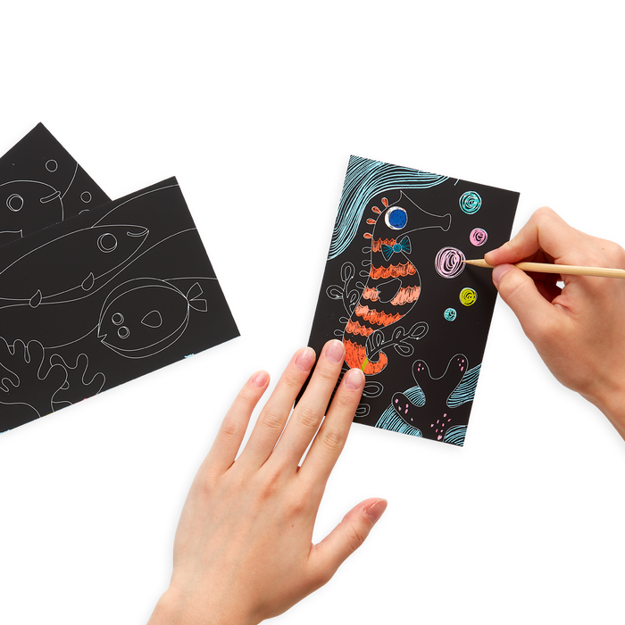 hands drawing on Friendly Fish Scratch and Scribble Mini Scratch Art Kit