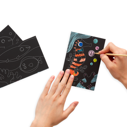 hands drawing on Friendly Fish Scratch and Scribble Mini Scratch Art Kit