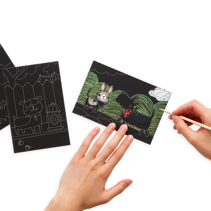 Hands scratching the Playful Pups Scratch and Scribble Mini Scratch Art Kit with the included wooden stylus