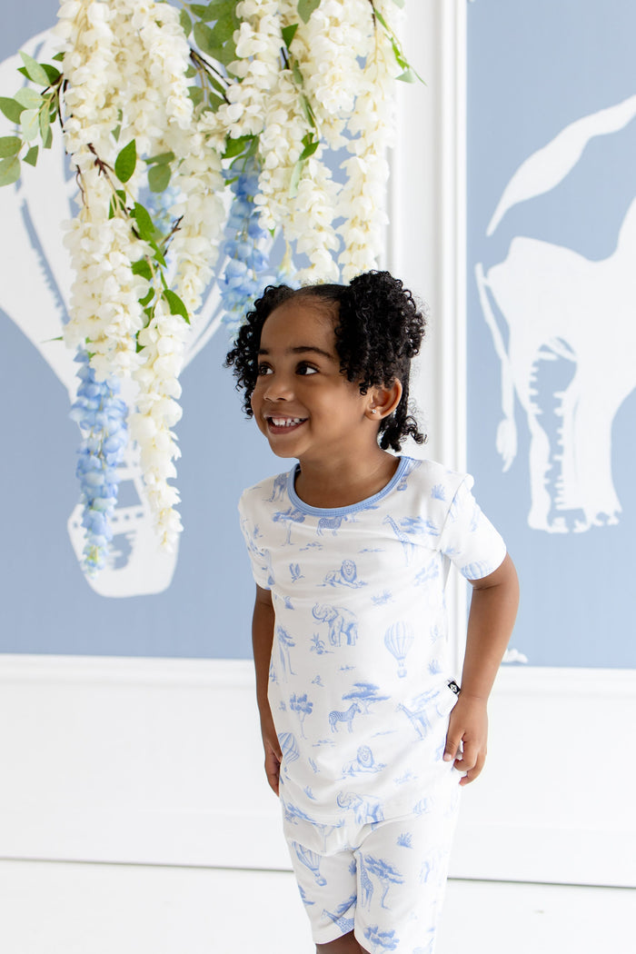 Young girl looking off to the side modeling the Short Sleeve Pajamas in Toile Safari standing in front of a safari inspired backdrop
