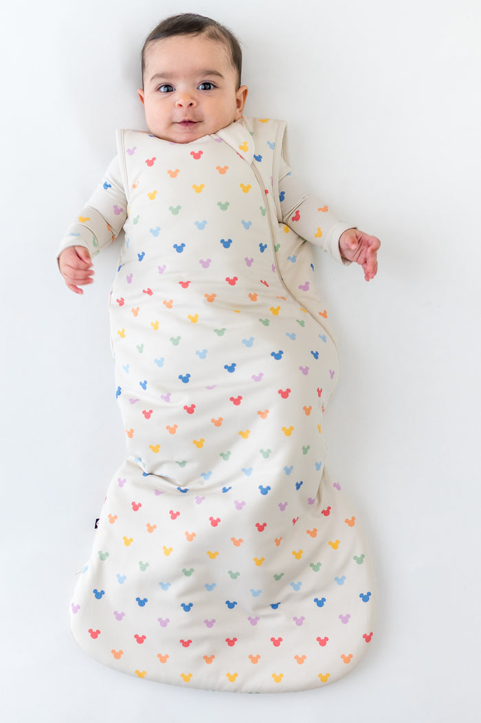 Baby in mickey head patterned sleep sack on white background