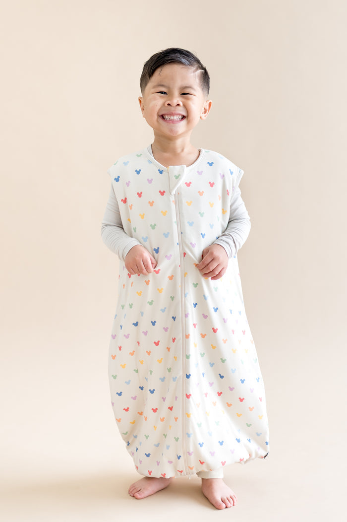 Young boy wearing sleep bag walker with colorful mickey head pattern