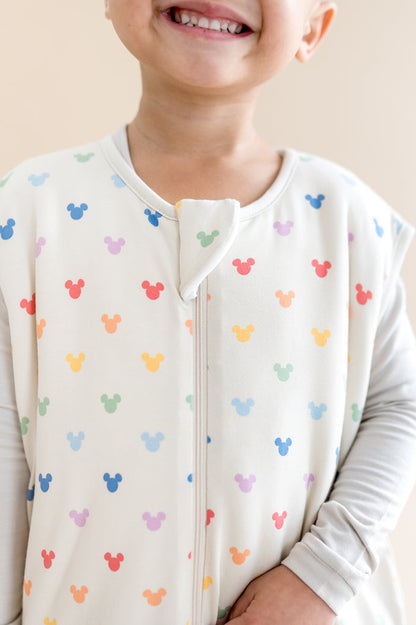 Child wearing a colorful Mickey Mouse patterned shirt with a plain background