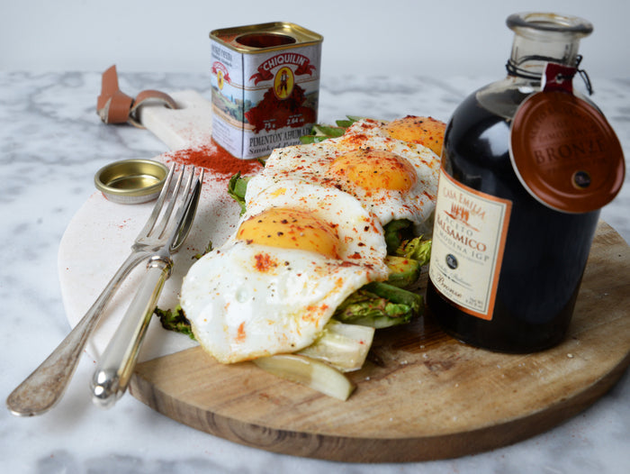 Eggs and avocado on a platter with a bottle of bronze balsamic and can of paprika