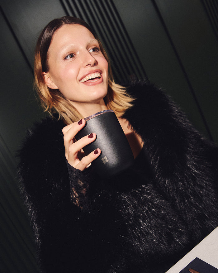 Woman enjoying coffee with Steel Cup Set at café.