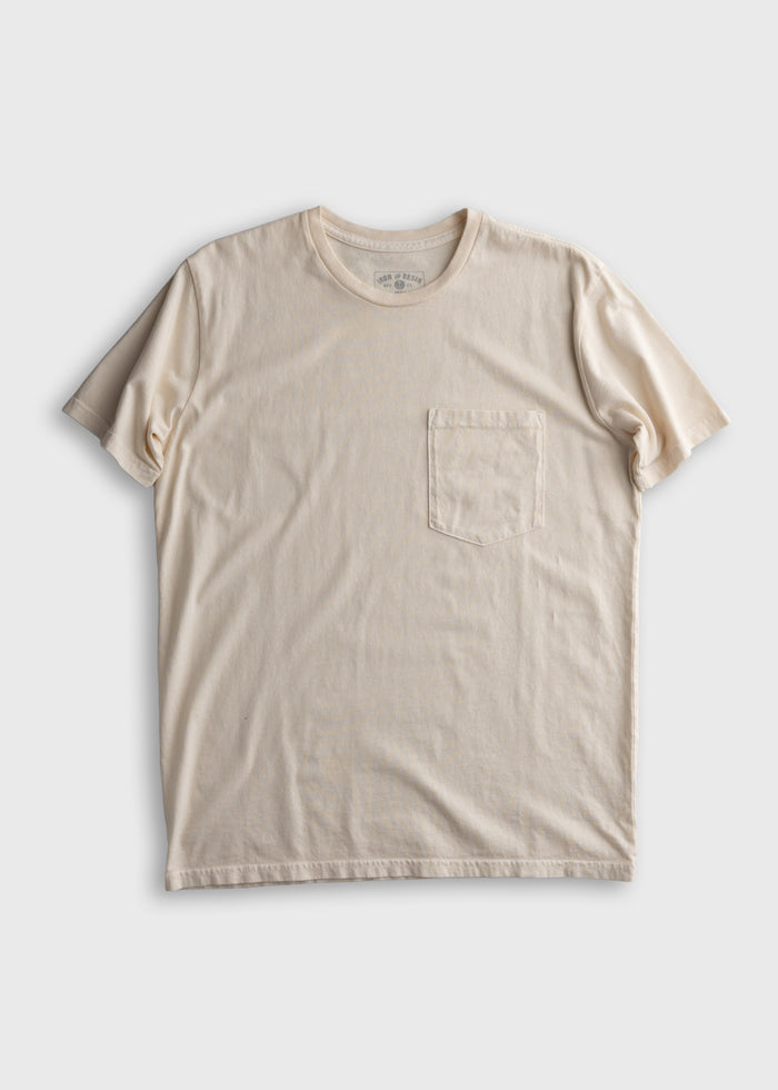 Cream-colored T-shirt with a round neck and a chest pocket, displayed flat on a plain white background.