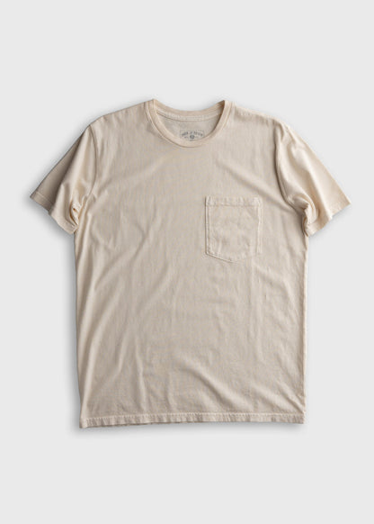 Cream-colored T-shirt with a round neck and a chest pocket, displayed flat on a plain white background.