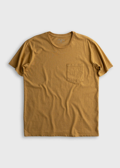 A mustard yellow T-shirt with a chest pocket, laid flat on a light gray background, showcasing its casual style and simple design.