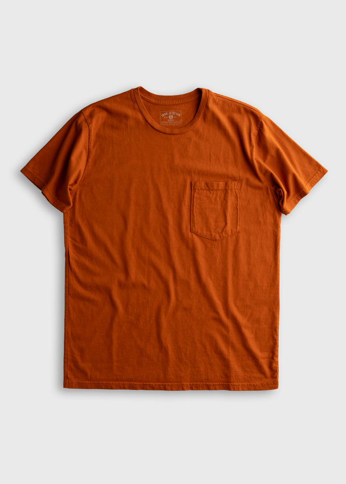 Orange T-shirt with a chest pocket, laid flat on a white background. Simple design, short sleeves, crew neck.