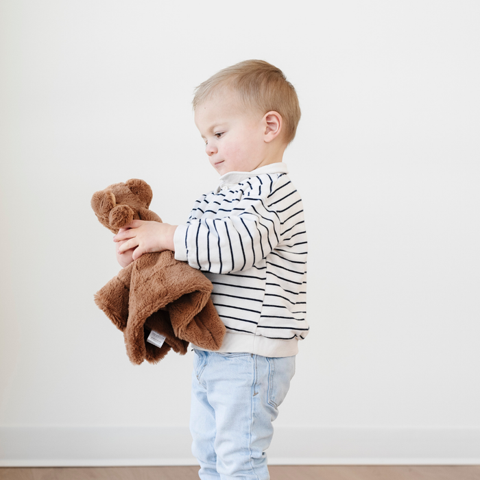 A little boy holds a brown dog stuffed animal lovey. This stuffed animal is a great gift for toddlers, baby gift, or addition to a nursery.