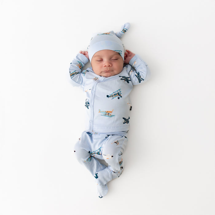 Newborn laying on a white surface wearing the Take Me Home Set with Cap in Take Off