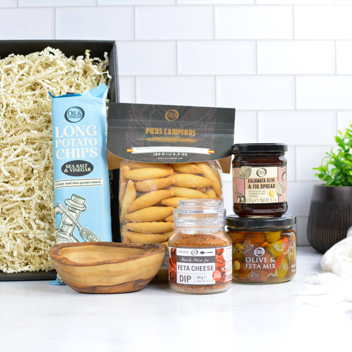 Assorted food items including potato chips, dips, and spreads on a white surface with a tiled wall background.