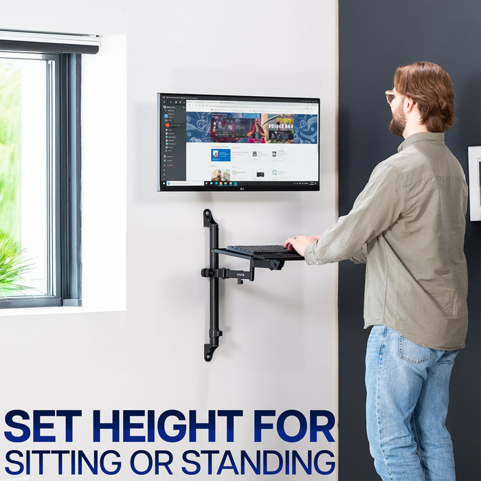 Person using a standing workstation with a mounted monitor and floating keyboard tray in an office setting.