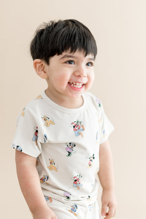 Child wearing a white t-shirt with colorful cartoon character prints on a beige background