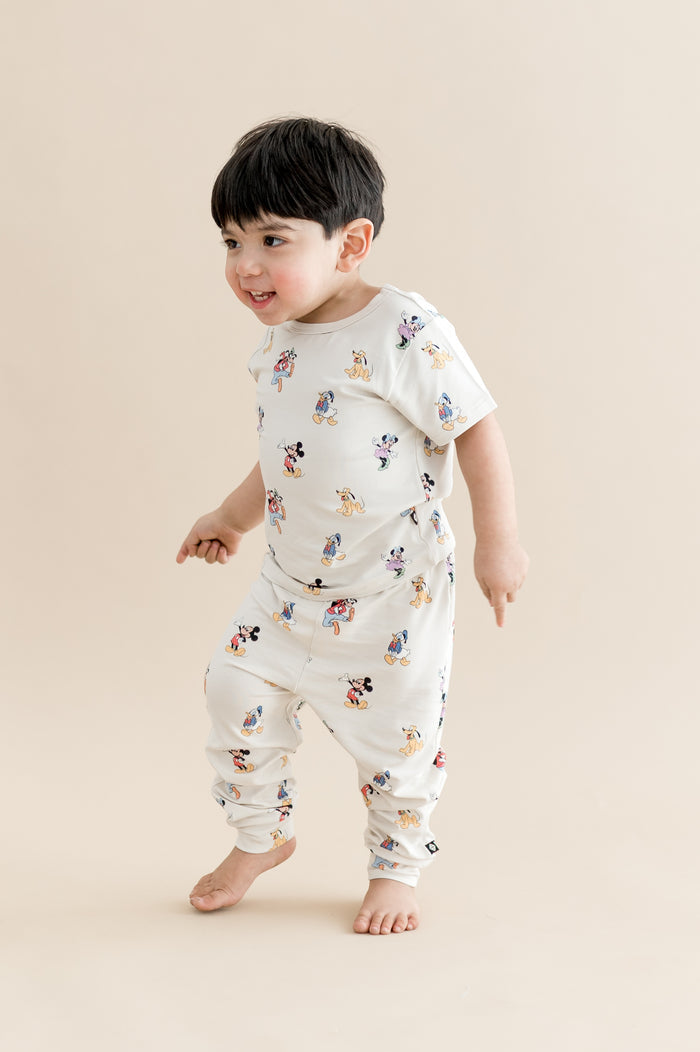 Child wearing a white outfit with cartoon character print on a beige background