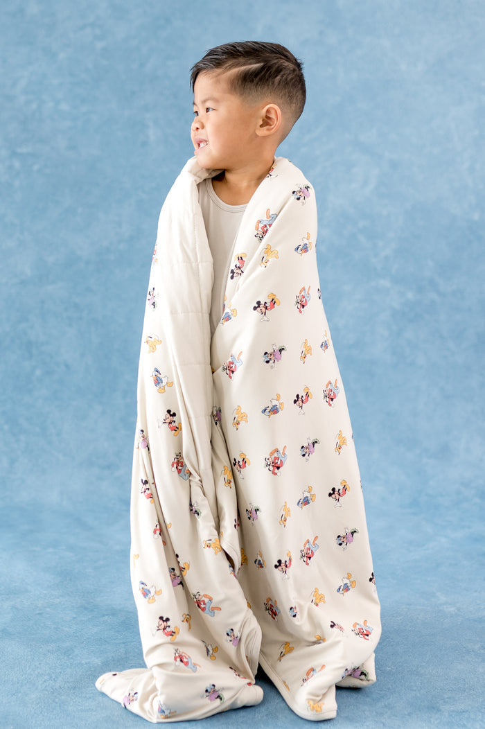 Toddler boy wrapped in a cream colored toddler blanket with mickey and friends pattern