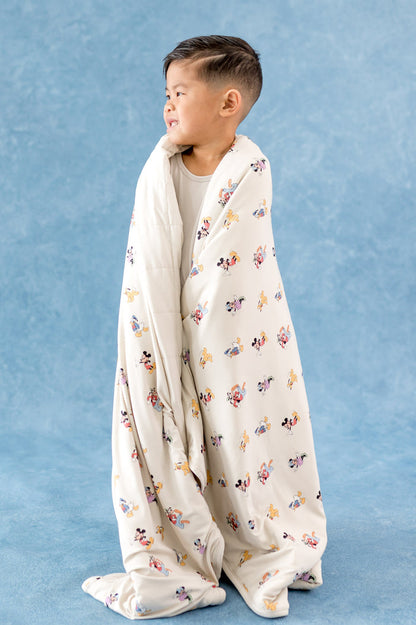 Toddler boy wrapped in a cream colored toddler blanket with mickey and friends pattern