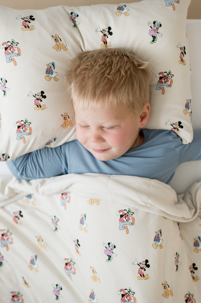 Child lying in bed with cartoon-themed bedding and pillow