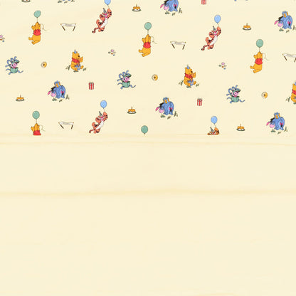 Close up of the Toddler Blanket in Winnie the Pooh Celebration 1.0 showing the quilted yellow backing and printed smooth top layer