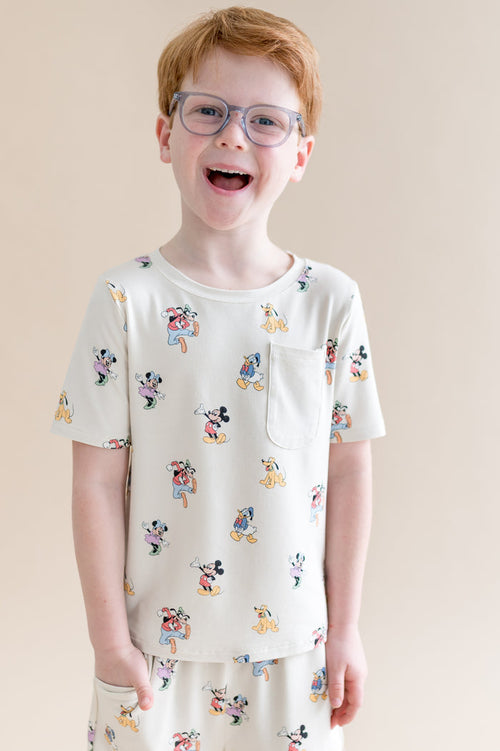 Child wearing a white t-shirt with cartoon mickey character print on a beige background