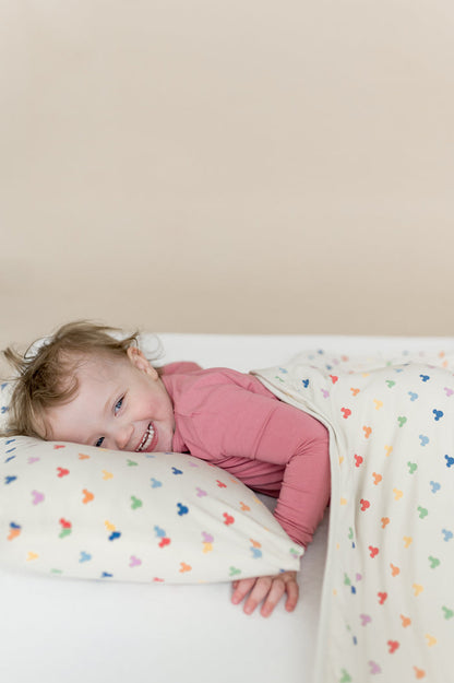Child laying on a pillow and with a blanket that has mickey head pattern