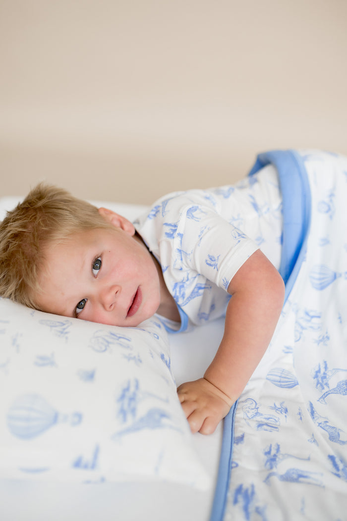 Young boy laying in bed resting his head on the Toddler Pillowcase in Toile Safari