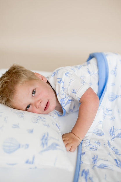 Young boy laying in bed resting his head on the Toddler Pillowcase in Toile Safari