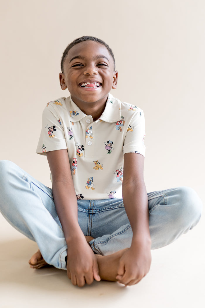 Child wearing jeans and short sleeve polo with mickey and friends pattern