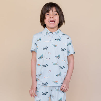 Smiling boy wearing the Toddler Short Sleeve Polo in Take Off with matching shorts
