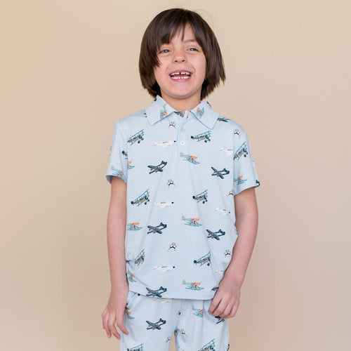 Smiling boy wearing the Toddler Short Sleeve Polo in Take Off with matching shorts