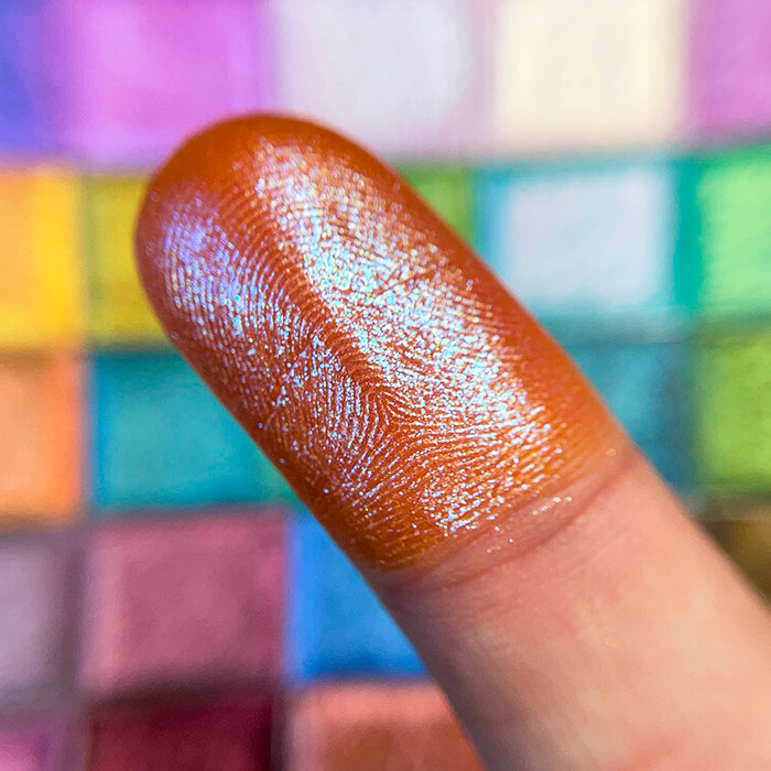 Close up finger swatch on fair skin tone of Trinket Glitter Multichrome Eyeshadow