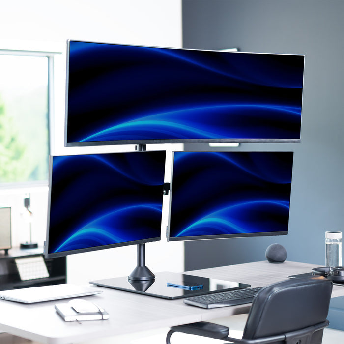 Three computer monitors on a desk with a modern office background