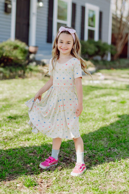 Child wearing Twirl Dress in Pastel Micky standing outdoors on a grass
